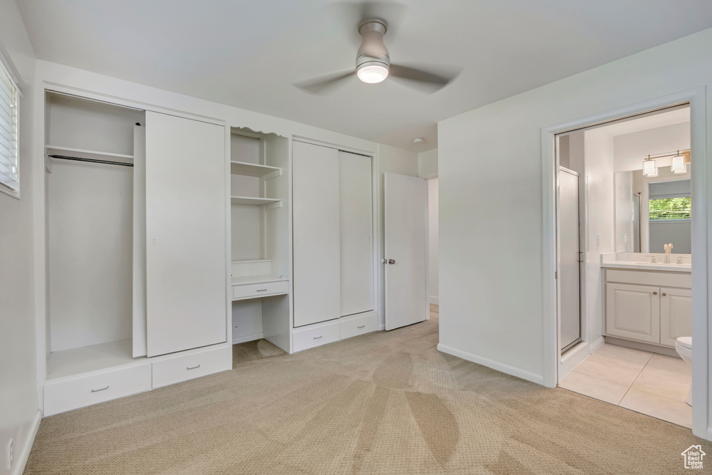 Unfurnished bedroom with two closets, light colored carpet, ensuite bath, an office area, and ceiling fan