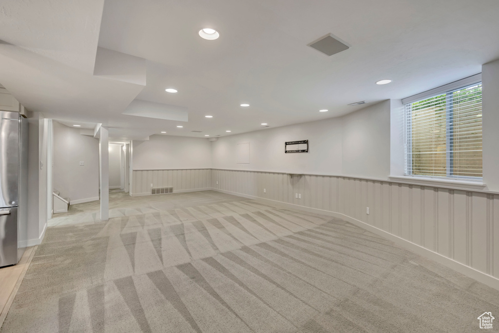 Basement featuring wainscoting, light carpet, recessed lighting, and stainless steel refrigerator