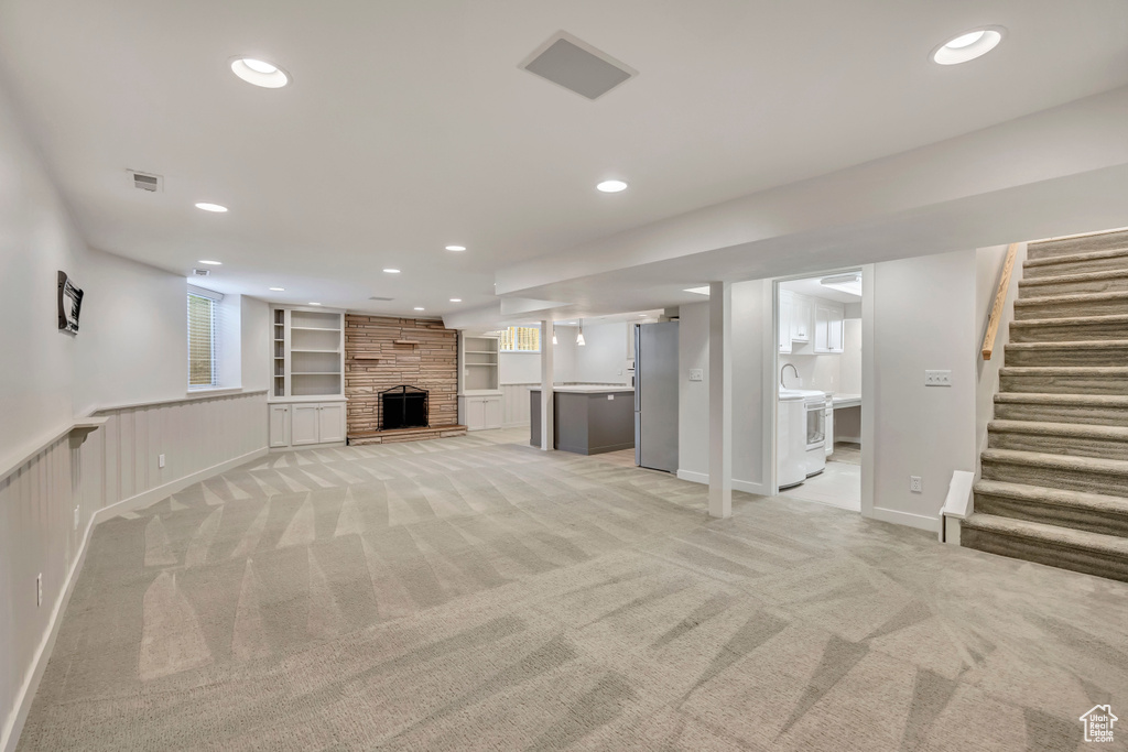 Unfurnished living room featuring recessed lighting, light carpet, stairway, a fireplace, and healthy amount of natural light
