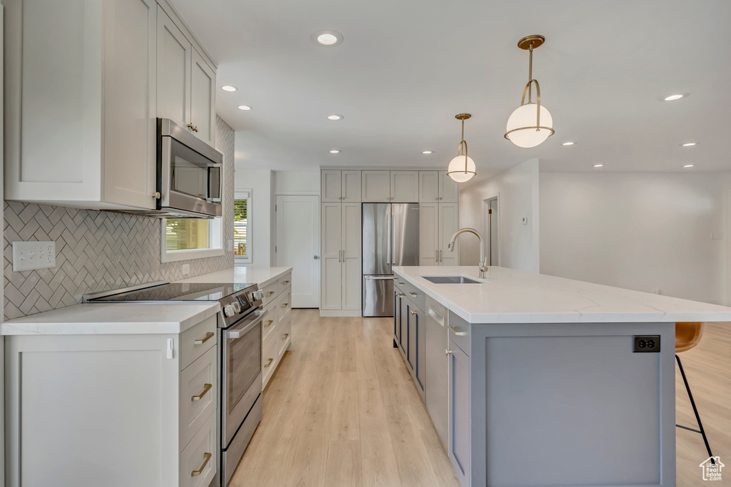 Kitchen featuring appliances with stainless steel finishes, tasteful backsplash, light wood-type flooring, a kitchen breakfast bar, and recessed lighting