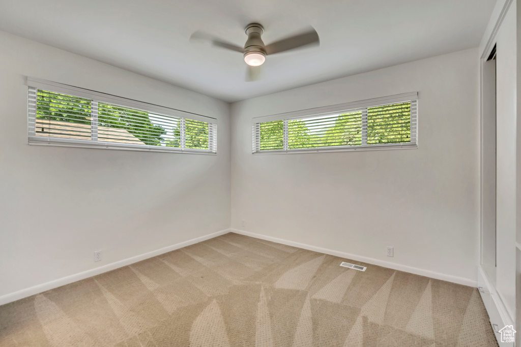 Spare room with light carpet and a ceiling fan