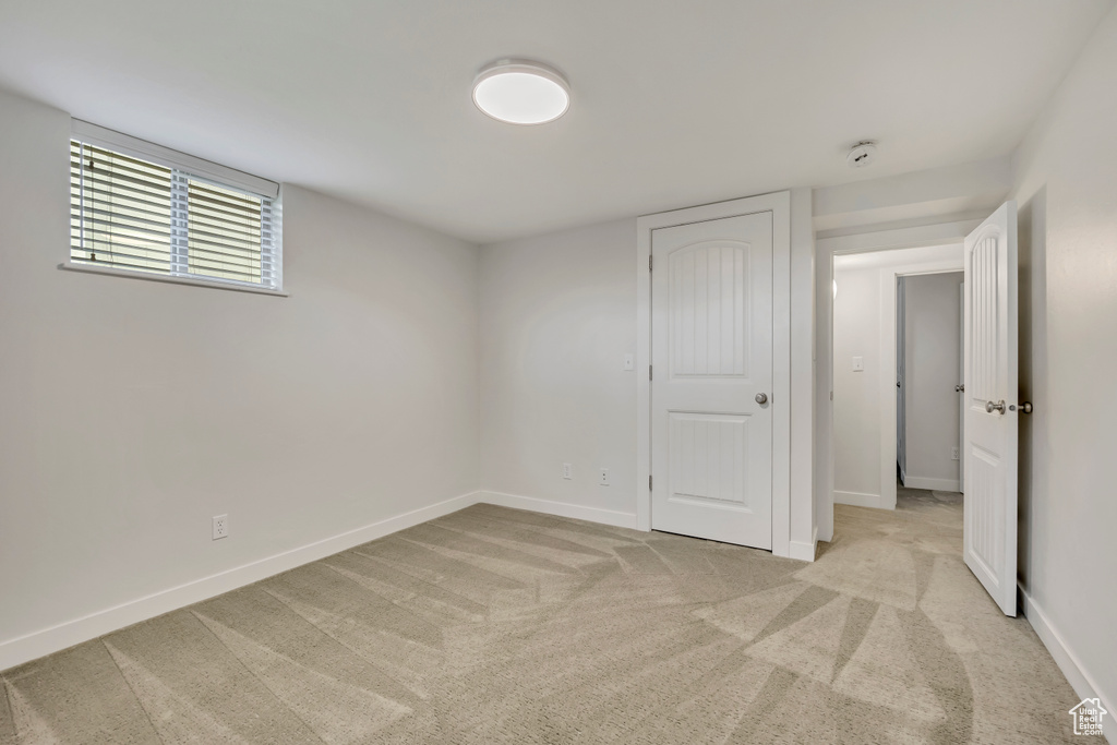 Unfurnished bedroom with light colored carpet and baseboards