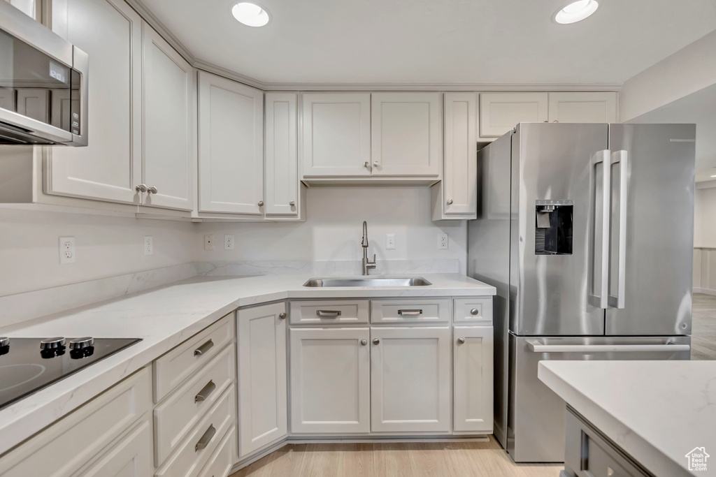 Kitchen with stainless steel appliances, light stone countertops, light wood-style floors, recessed lighting, and white cabinets