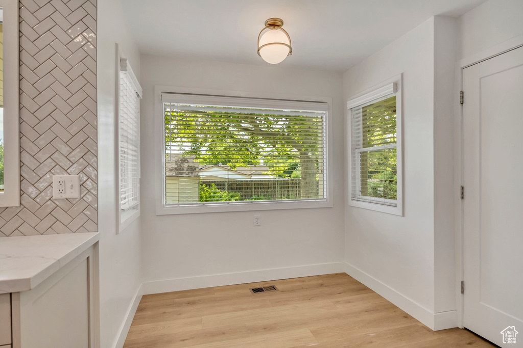 Unfurnished dining area with baseboards and light wood finished floors