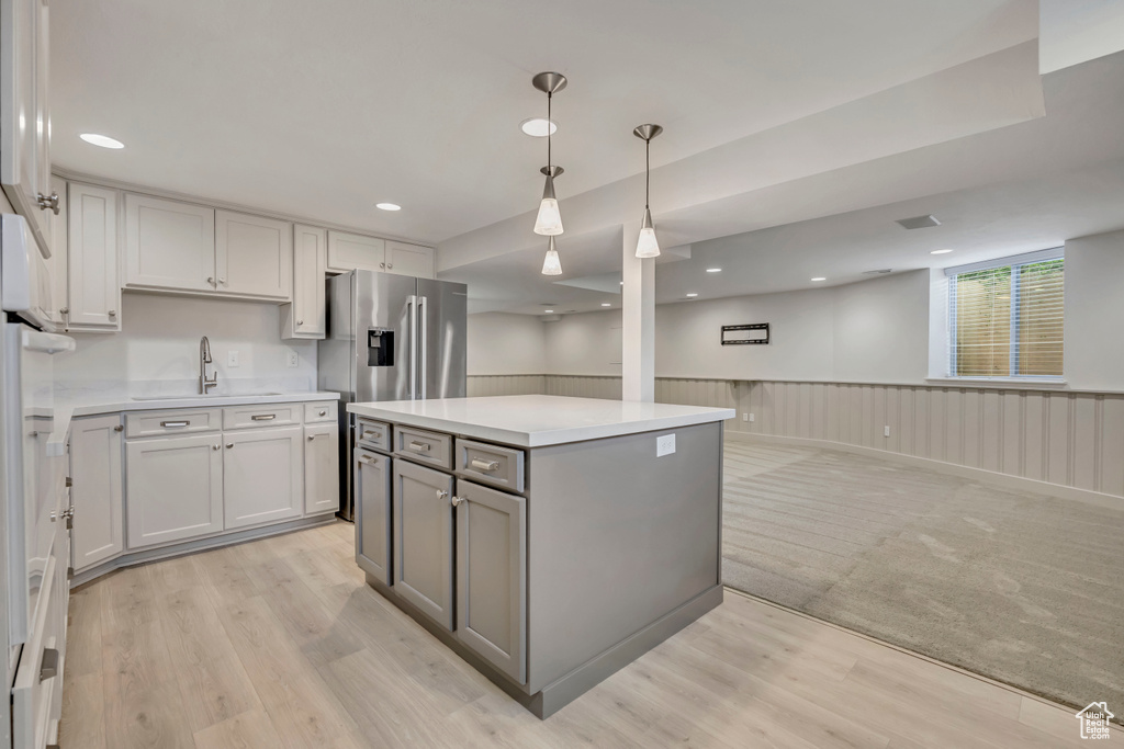 Kitchen featuring gray cabinets, light countertops, light wood-style flooring, wainscoting, and pendant lighting