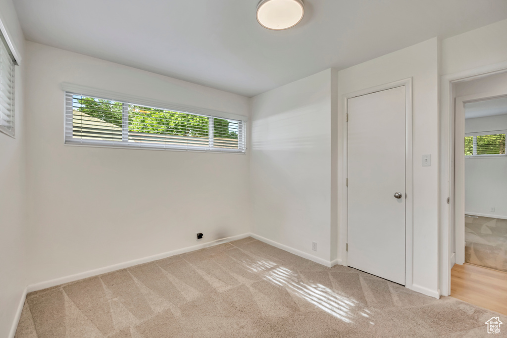 Unfurnished bedroom with light carpet and multiple windows