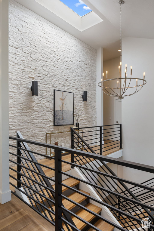 Stairs with a skylight, wood finished floors, and a chandelier