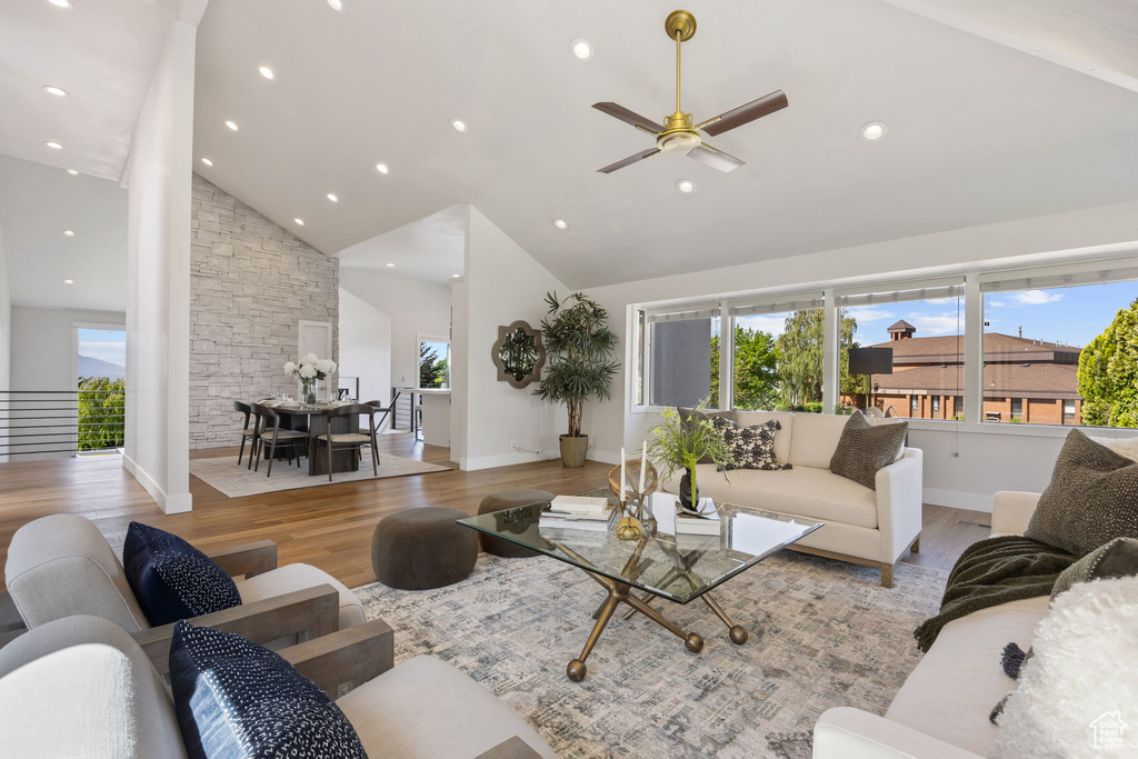 Living room featuring plenty of natural light, high vaulted ceiling, ceiling fan, light wood-style floors, and recessed lighting