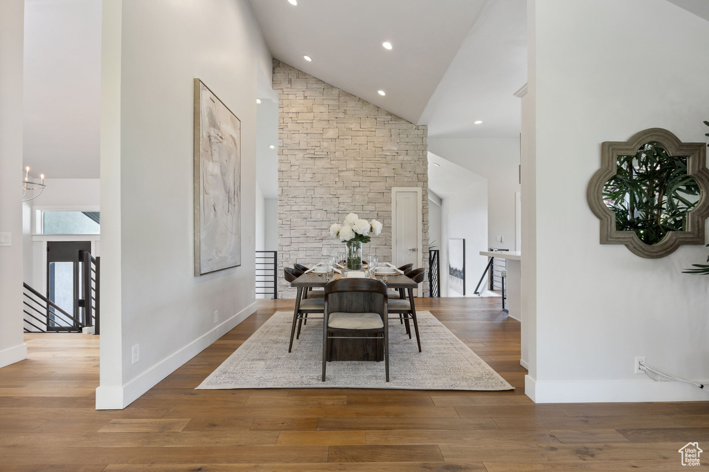 Dining space with high vaulted ceiling, wood finished floors, a chandelier, and recessed lighting