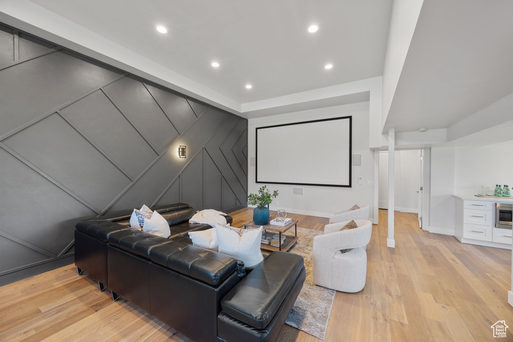 Cinema featuring light wood-style floors, a decorative wall, and recessed lighting