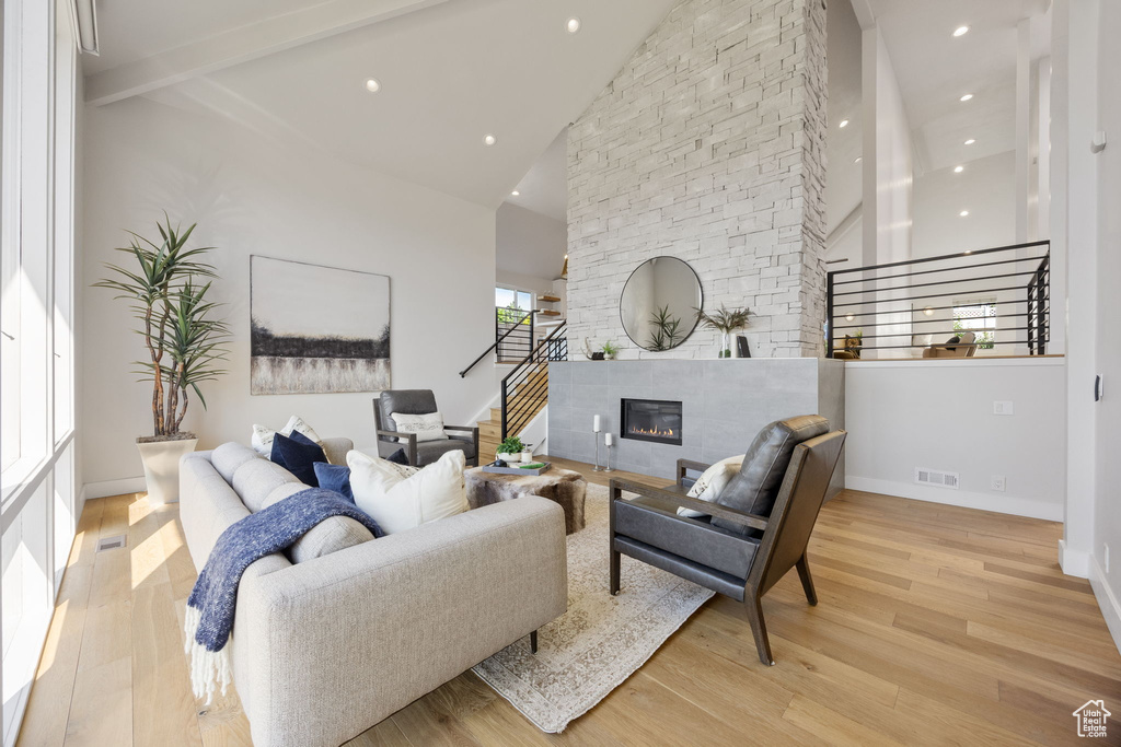 Living area with high vaulted ceiling, light wood-type flooring, stairway, a fireplace, and recessed lighting
