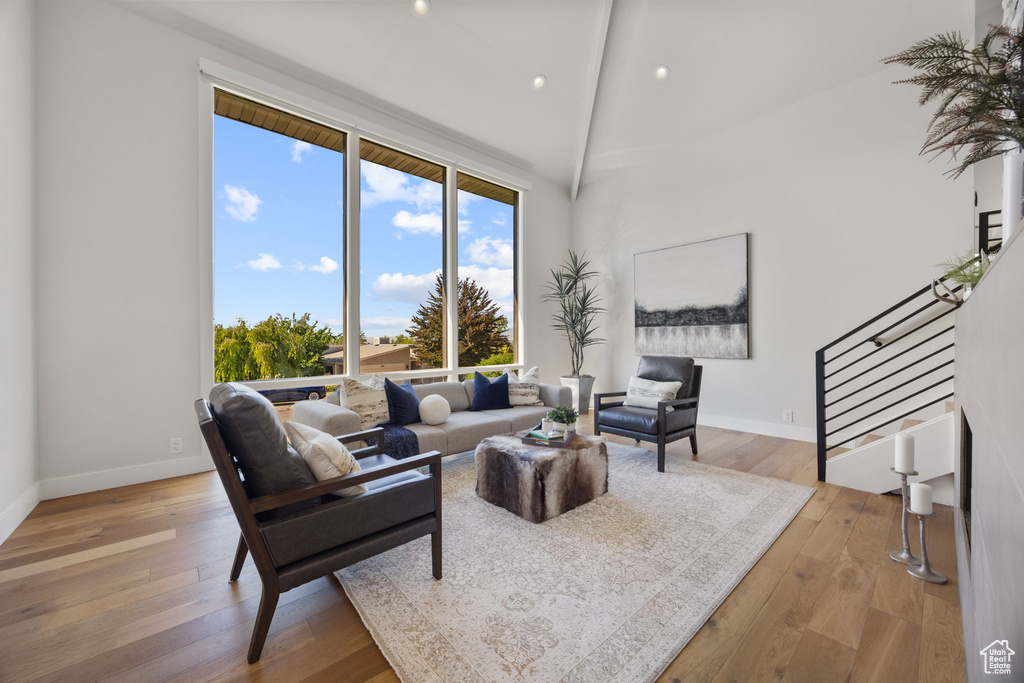 Living area with stairway, light wood-type flooring, high vaulted ceiling, and recessed lighting
