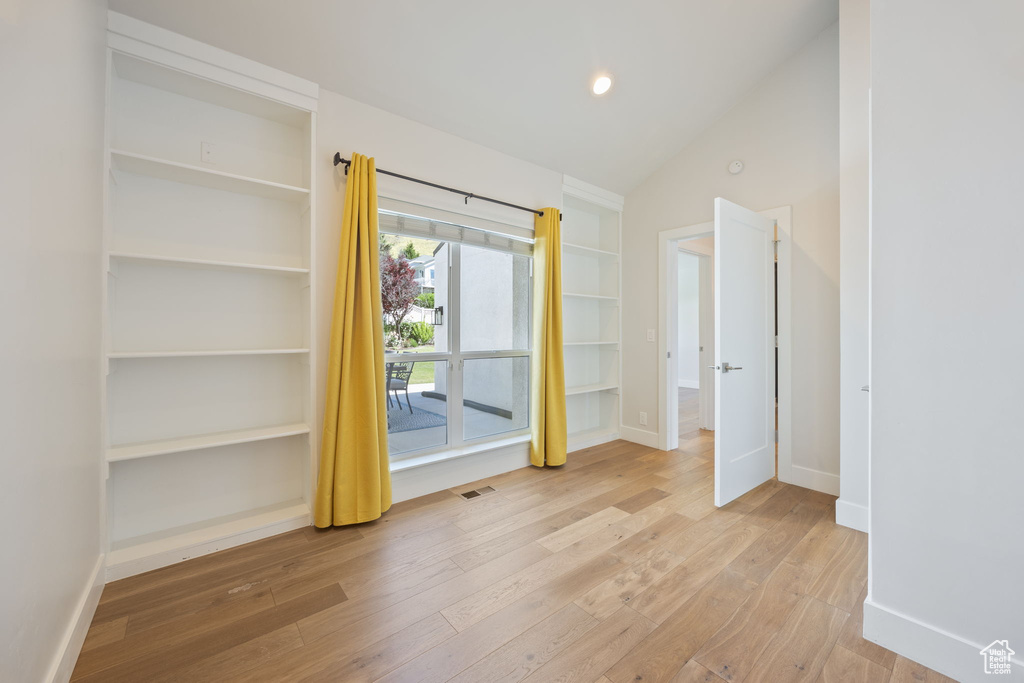 Unfurnished bedroom featuring hardwood / wood-style floors and vaulted ceiling