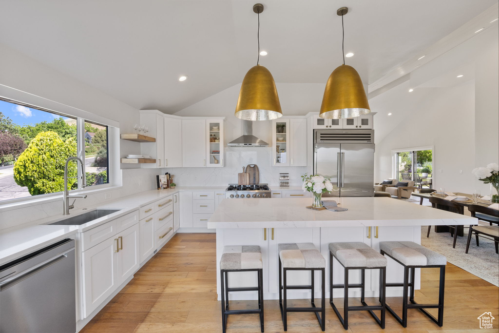 Kitchen with appliances with stainless steel finishes, a breakfast bar area, light countertops, a kitchen island, and pendant lighting