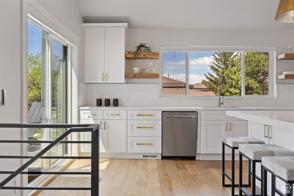 Kitchen with open shelves, dishwasher, healthy amount of natural light, and tasteful backsplash