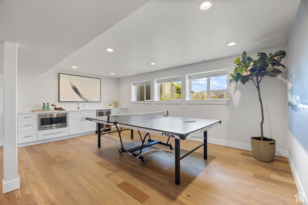 Rec room with light wood-style flooring, recessed lighting, and beverage cooler