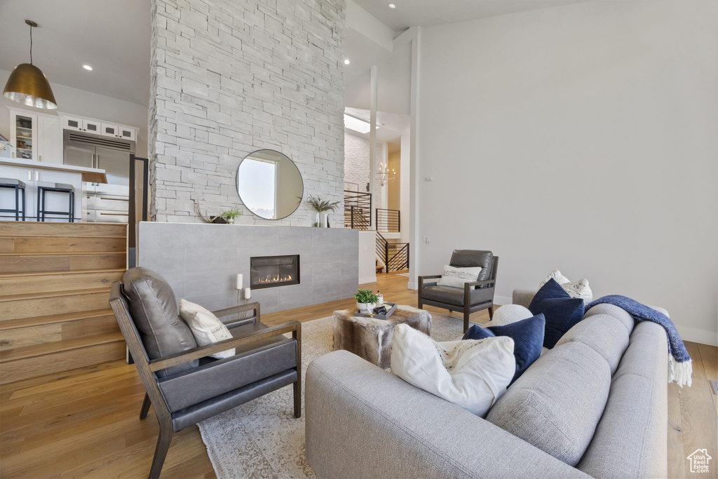 Living room featuring wood finished floors, recessed lighting, a fireplace, and a towering ceiling