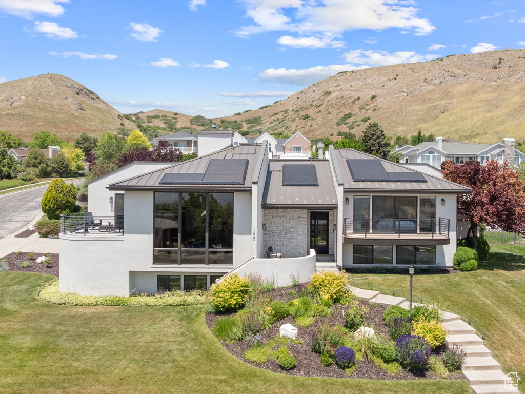 Rear view of property featuring stucco siding, a standing seam roof, solar panels, and a mountain view