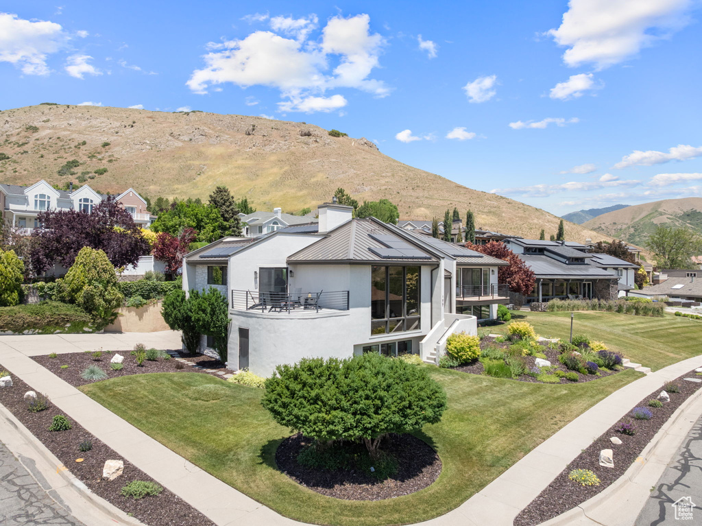 Back of house featuring a balcony, a mountain view, stucco siding, a yard, and a residential view
