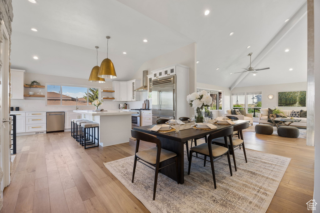 Dining area with healthy amount of natural light, ceiling fan, light wood-type flooring, high vaulted ceiling, and recessed lighting