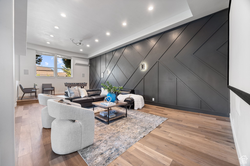 Living room with a decorative wall, recessed lighting, and wood finished floors