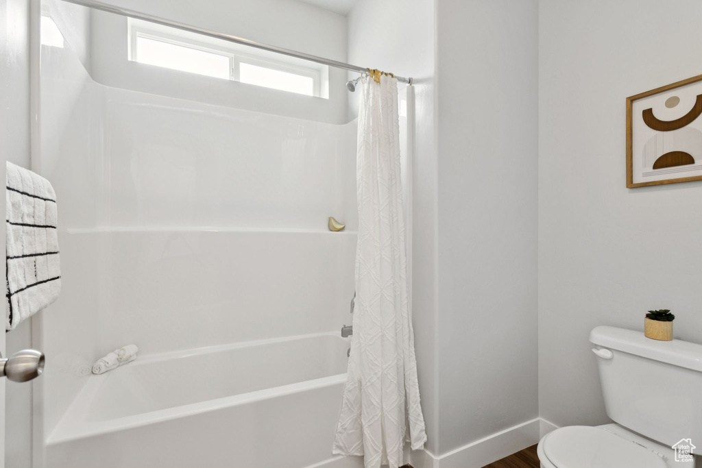 Full bathroom with shower / tub combo with curtain and wood finished floors