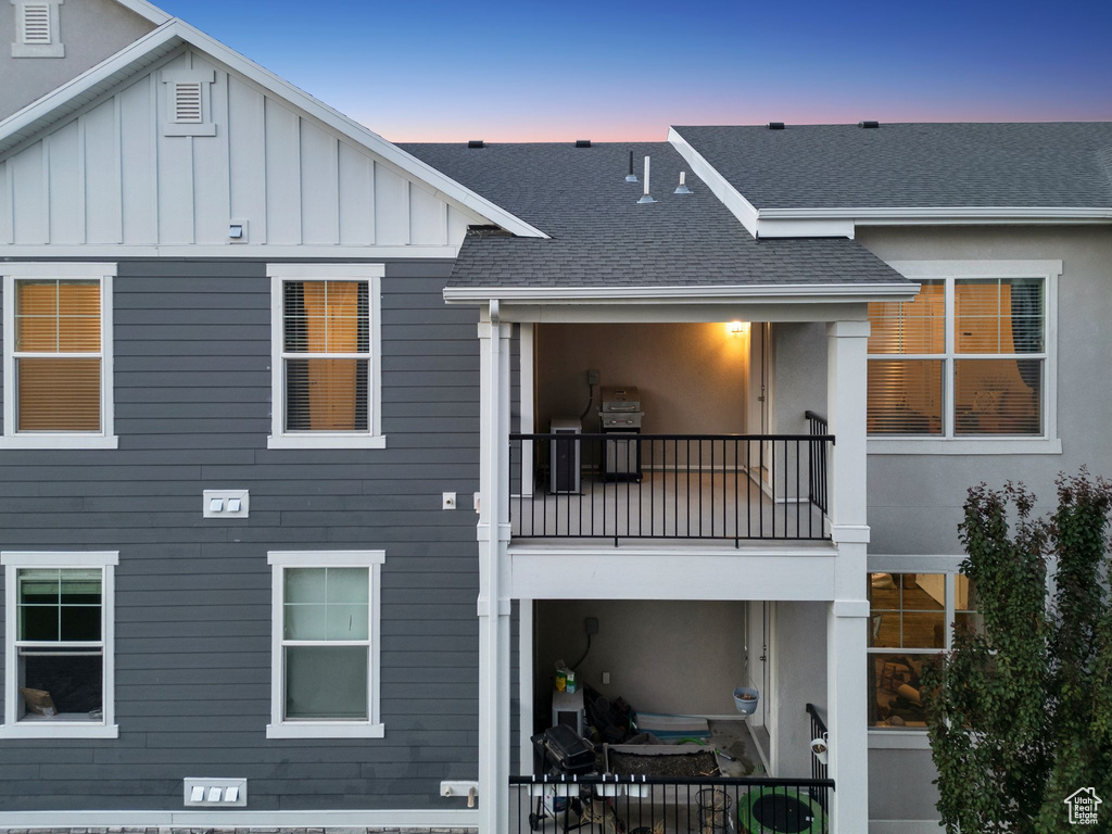 Rear view of house featuring a balcony, a shingled roof, and board and batten siding