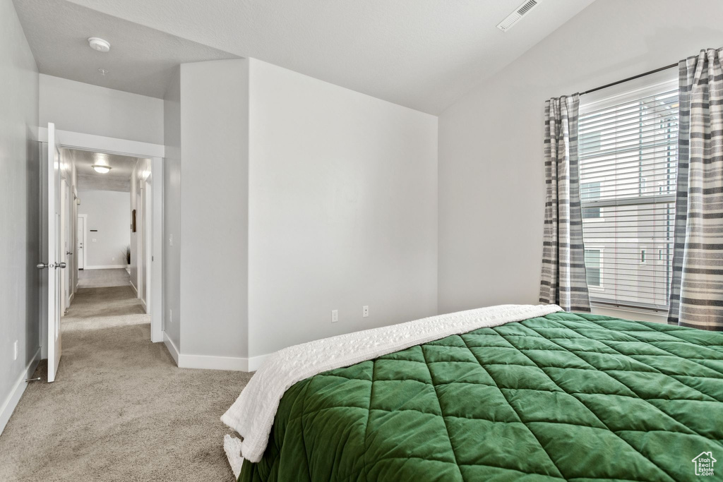 Bedroom with light carpet and vaulted ceiling