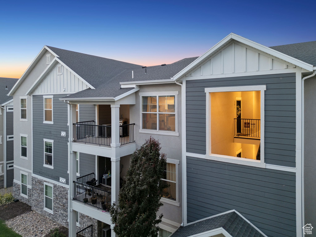 Back of property featuring board and batten siding, a balcony, and a shingled roof