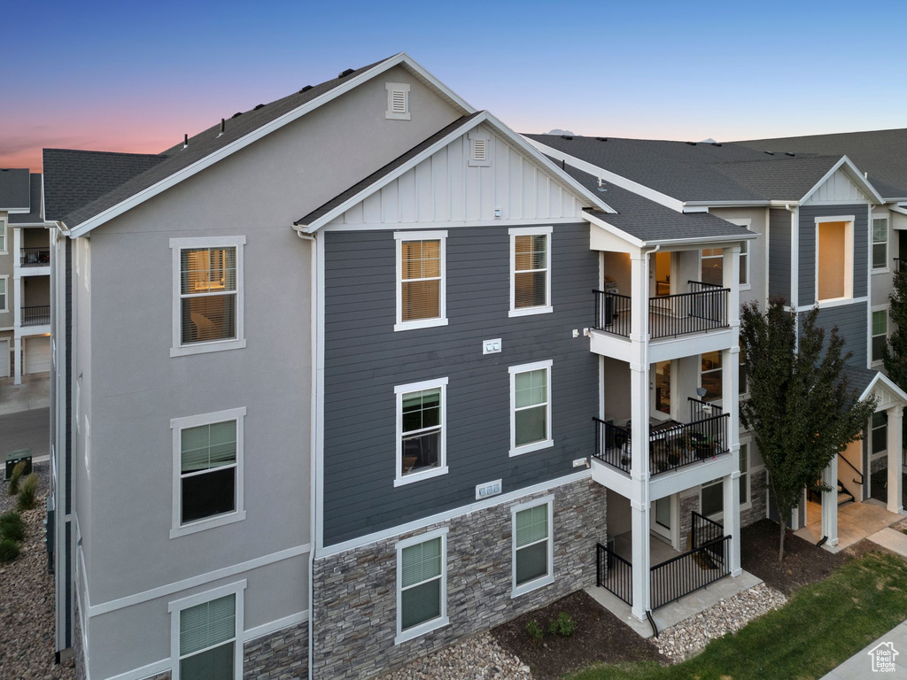 Back of property with a balcony, stone siding, board and batten siding, and stucco siding