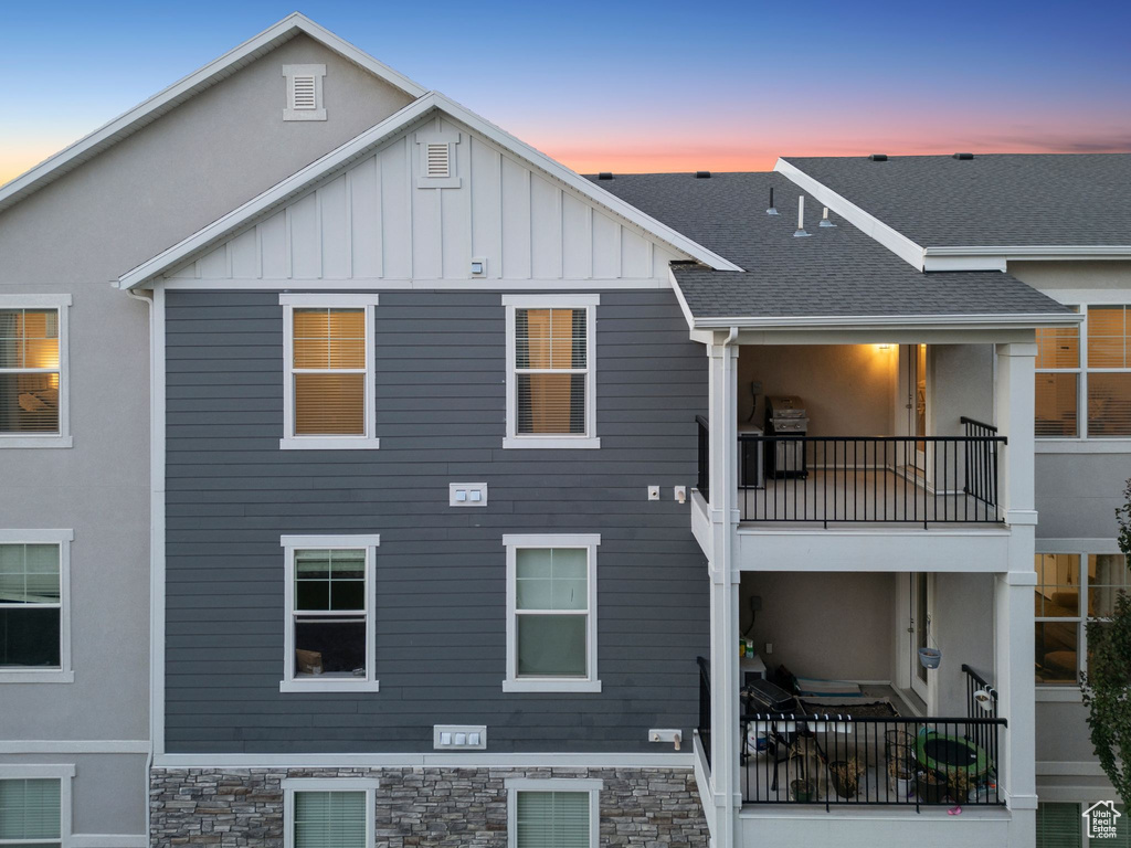 Back of house featuring a balcony, board and batten siding, a shingled roof, and stucco siding