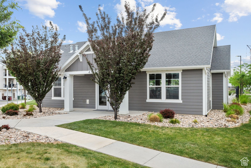 View of front of house with a front lawn, a shingled roof, and concrete driveway