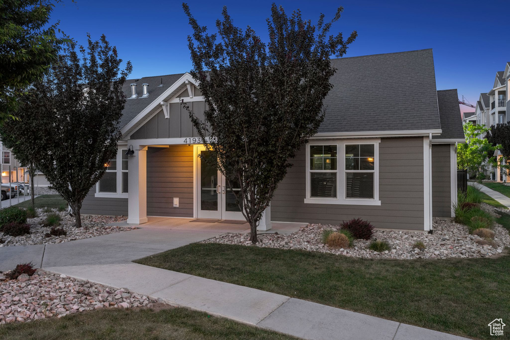 View of front of house with french doors, a front lawn, and a shingled roof