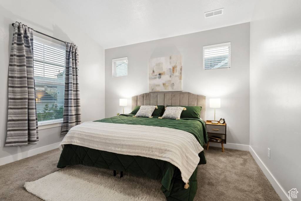 Carpeted bedroom featuring multiple windows and lofted ceiling