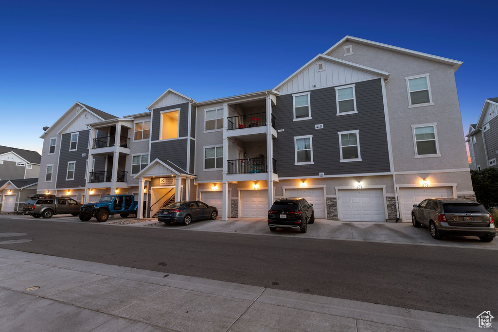 Multi unit property with board and batten siding, an attached garage, driveway, and stone siding