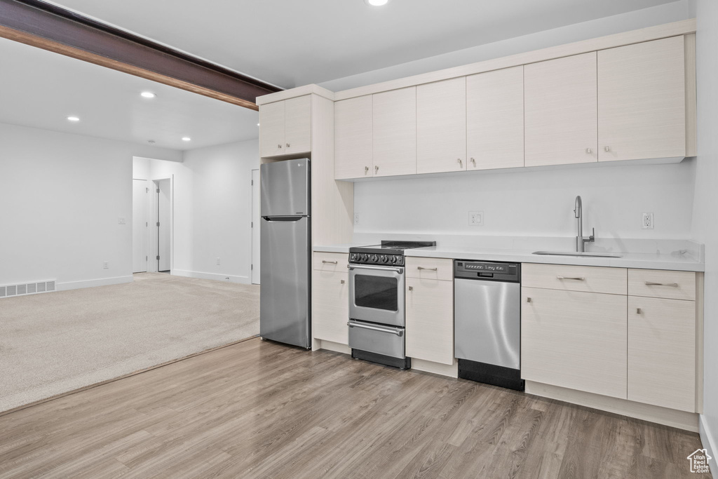 Kitchen featuring stainless steel appliances, recessed lighting, light countertops, light wood-style flooring, and open floor plan
