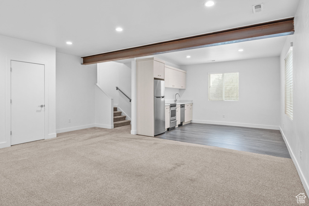 Unfurnished living room with carpet flooring, stairway, and recessed lighting