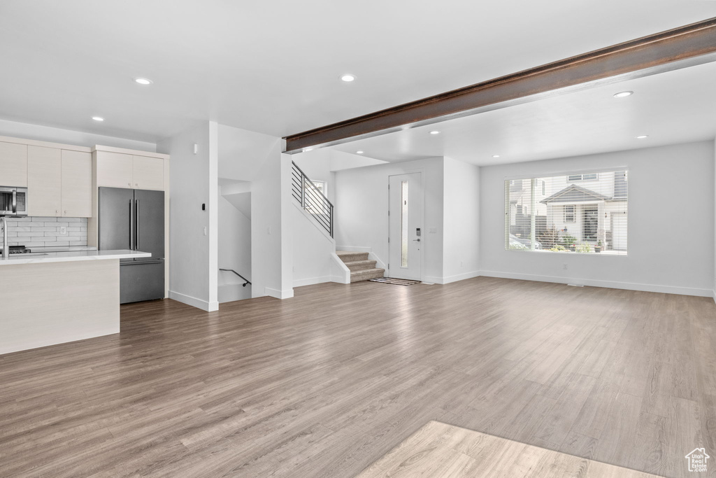 Unfurnished living room featuring recessed lighting, light wood finished floors, and stairs