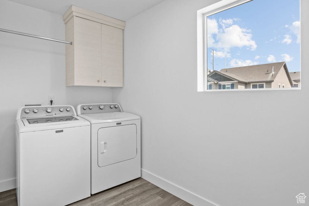 Washroom featuring washer and clothes dryer, light wood finished floors, and cabinet space