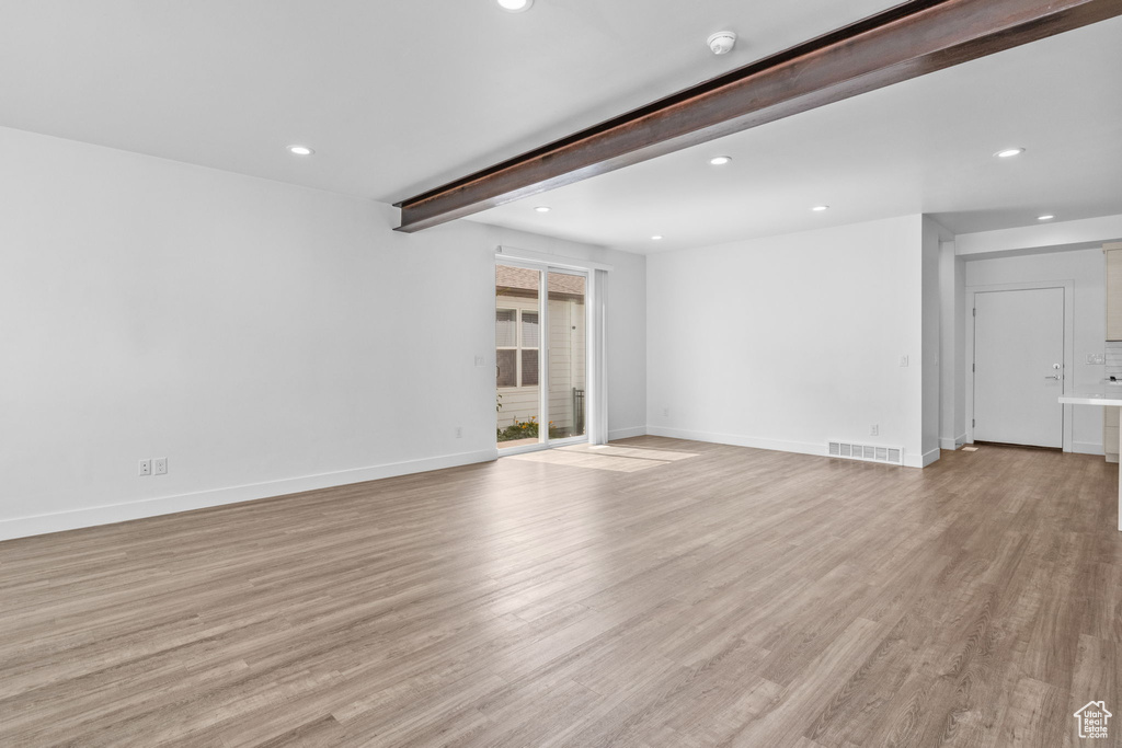 Unfurnished living room featuring beamed ceiling, recessed lighting, and light wood-type flooring