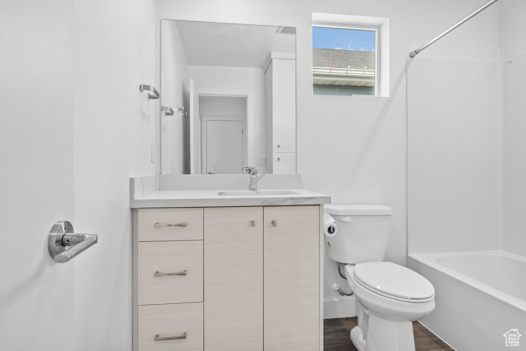 Full bath featuring vanity, washtub / shower combination, and wood finished floors