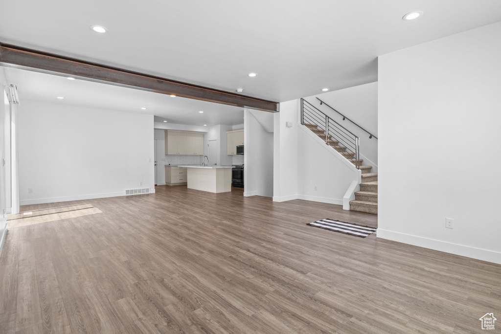 Unfurnished living room with recessed lighting, stairs, and light wood-style flooring