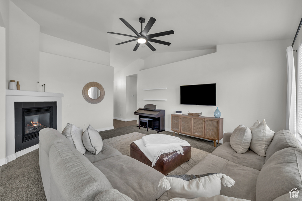 Carpeted living room with a ceiling fan, lofted ceiling, a tile fireplace, and healthy amount of natural light