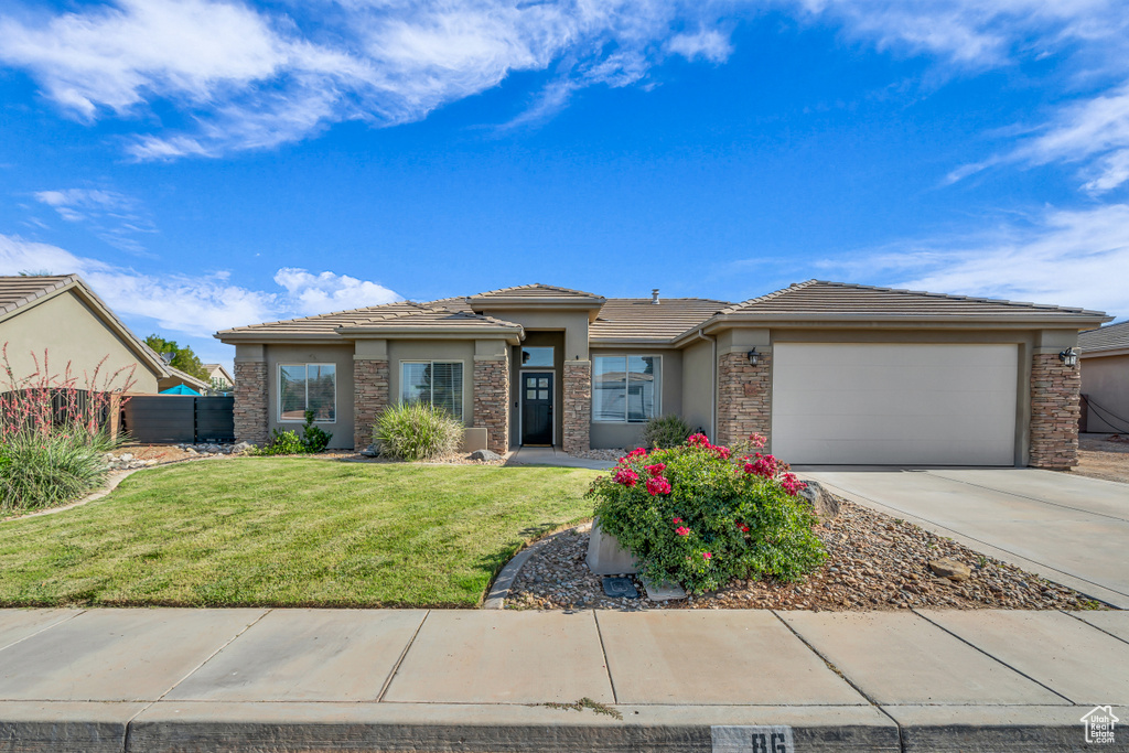 Prairie-style home featuring stucco siding, driveway, a garage, and a tiled roof