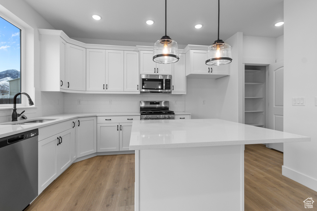 Kitchen featuring appliances with stainless steel finishes, light wood-type flooring, decorative backsplash, white cabinetry, and recessed lighting