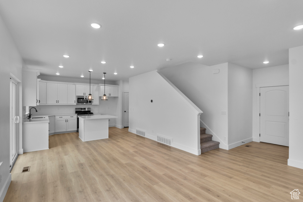 Kitchen with stainless steel appliances, light countertops, light wood-style floors, white cabinets, and recessed lighting