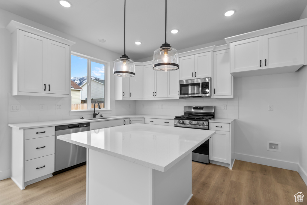 Kitchen featuring appliances with stainless steel finishes, white cabinetry, light countertops, backsplash, and recessed lighting