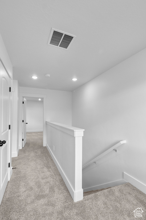 Hallway with carpet floors, an upstairs landing, and recessed lighting