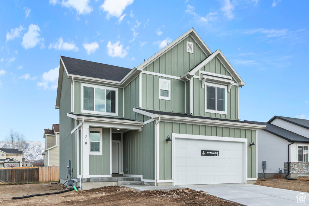 View of front of property with board and batten siding, concrete driveway, and an attached garage