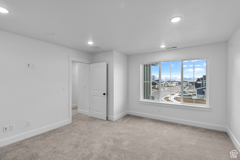 Carpeted empty room with recessed lighting and a smoke detector